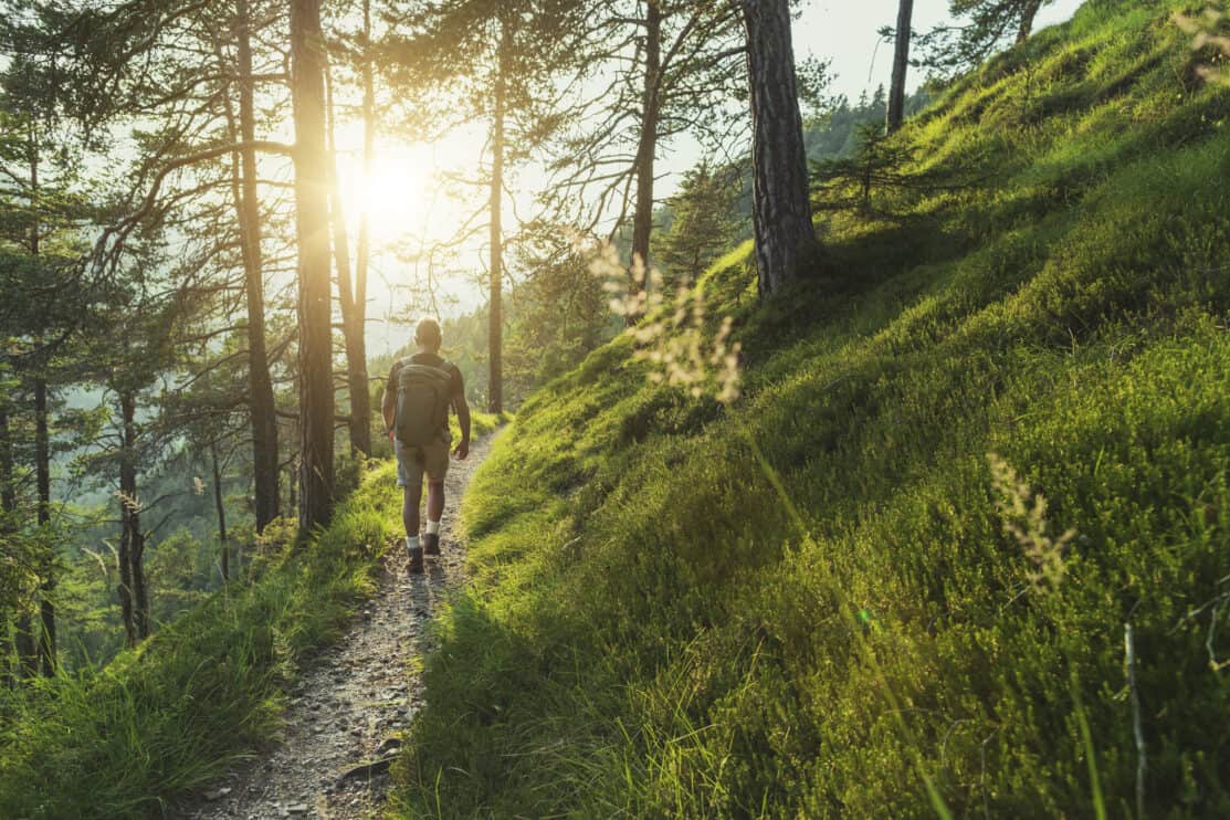 senior-man-trail-hiking-in-the-forest-at-sunset