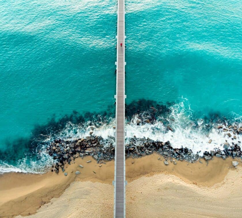 An aerial view of a wooden pier on a beach.