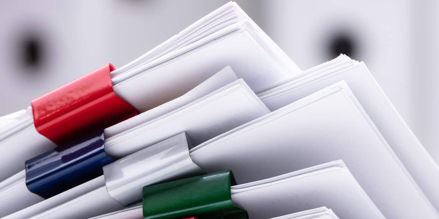 A stack of documents with colorful paperclips.