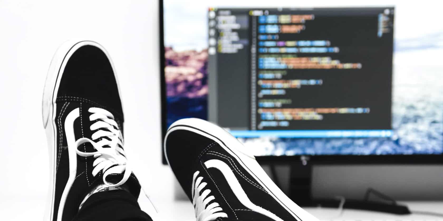 A person with their feet on a desk with a computer.